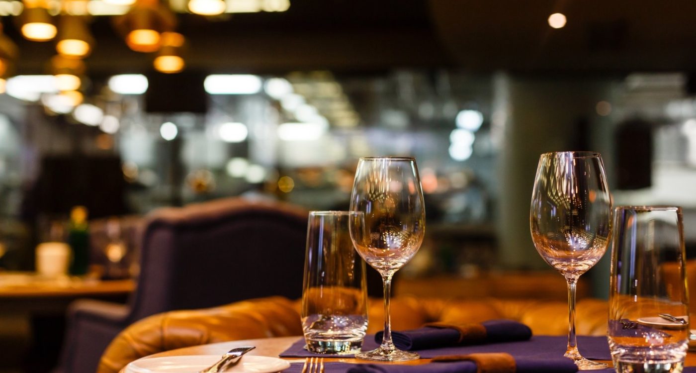 Two empty wine glasses sitting in a restaurant on a warm sunny afternoon.