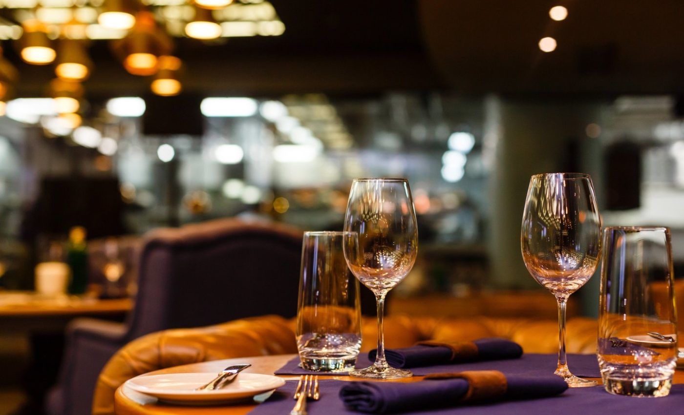 Two empty wine glasses sitting in a restaurant on a warm sunny afternoon.